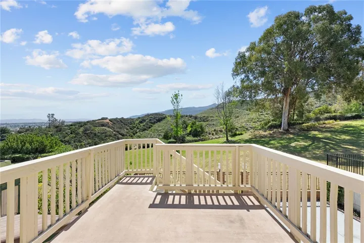 Expansive deck overlooks the grassy open space and surrounding hills, creating a peaceful setting for outdoor lounging.