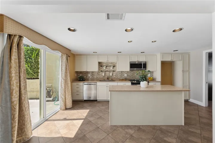 Updated kitchen features ample cabinetry, stainless steel appliances, a center island, and direct access to the patio for easy indoor-outdoor flow.