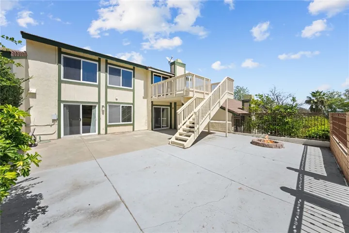 Rear elevation features multiple large windows, sliding glass doors, and an upper deck that extends the home’s indoor-outdoor living potential.
