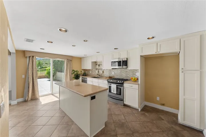 Well-appointed kitchen features abundant cabinetry, a center island, tile flooring, and a practical layout for meal prep and gathering.
