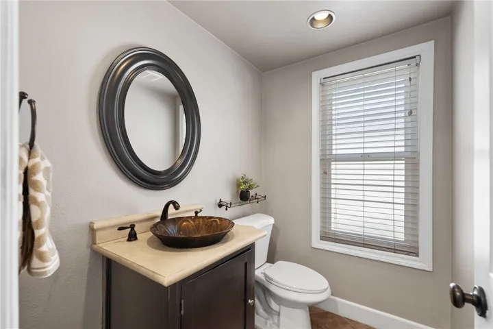 Main-level powder room includes a stylish vessel sink, window for natural light, and updated fixtures.