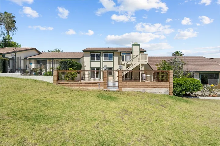Full rear view of the home highlights the elevated deck, fenced patio, and generous open space behind the property.