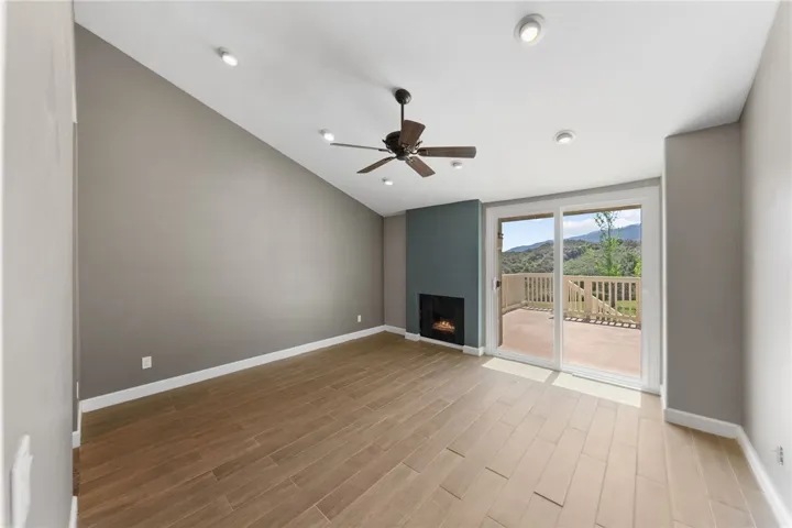  Check out the view!  Spacious primary bedroom features wood-look flooring, a ceiling fan, fireplace, and sliding glass doors leading directly to the private deck.