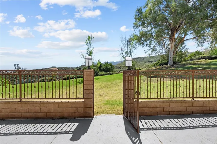 Gated access from the patio leads directly to the grassy rear area, framed by open views and established trees.