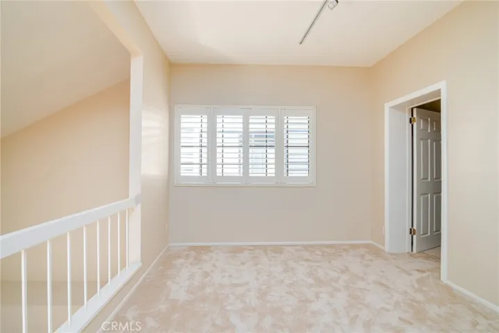 A second view of the spacious loft with a window that let's in warm light and has lovely plantation shutters.