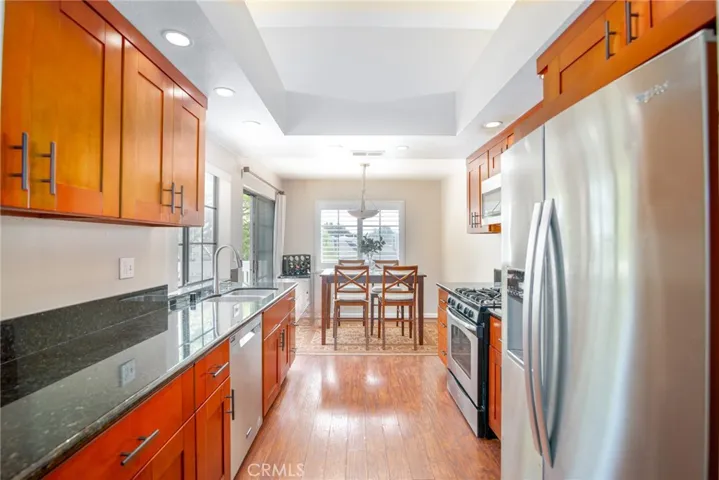The kitchen is light and cheery with granite countertops, laminate flooring, recessed lighting and warm wood cabinetry.