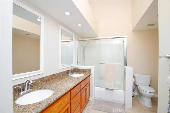 Primary ensuite bathroom features a spacious vanity with dual sinks, granite countertops, 2 mirrors, and tub/shower combo.