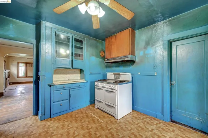Kitchen featuring double oven range, arched walkways, light countertops, ceiling fan, and parquet flooring