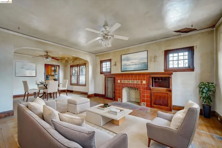 Living room with a tiled fireplace, ceiling fan, wood-type flooring, crown molding, and arched walkways