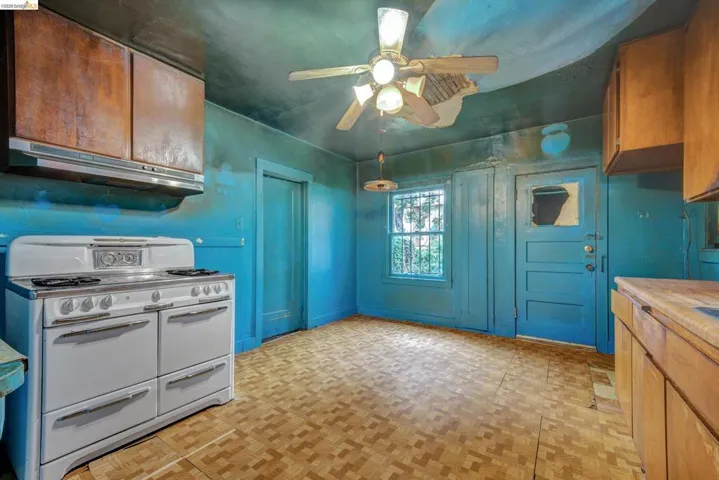Kitchen with range with two ovens, wood finish cabinetry, a ceiling fan, light countertops, and parquet flooring