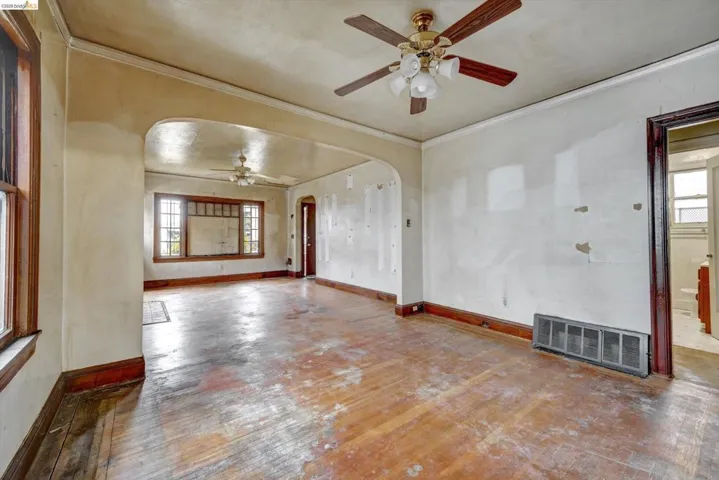 Unfurnished room with a ceiling fan, hardwood / wood-style floors, arched walkways, ornamental molding, and plenty of natural light