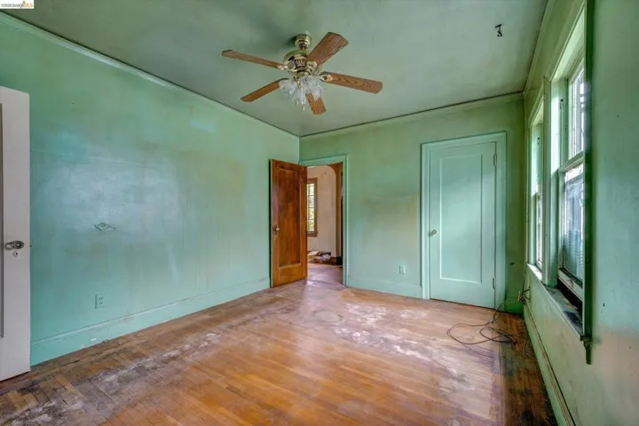 Unfurnished bedroom featuring wood-type flooring, baseboard heating, a ceiling fan, and crown molding