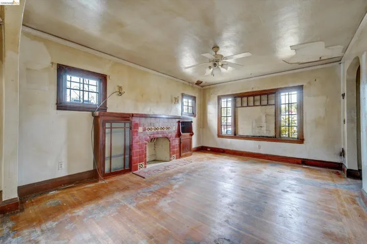 Unfurnished living room with hardwood / wood-style floors, a fireplace, ceiling fan, and ornamental molding