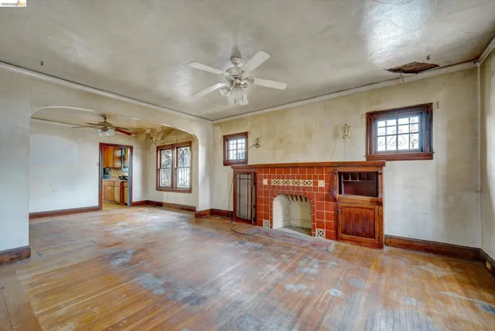 Unfurnished living room featuring hardwood / wood-style flooring, arched walkways, healthy amount of natural light, a fireplace, and crown molding