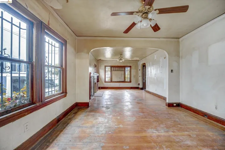 Unfurnished room with arched walkways, ceiling fan, light wood-style flooring, and ornamental molding