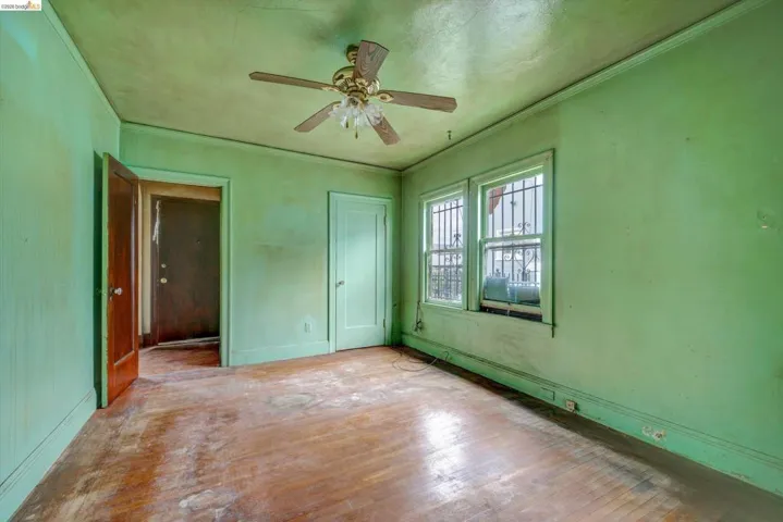 Unfurnished bedroom with hardwood / wood-style flooring, crown molding, a ceiling fan, and a closet