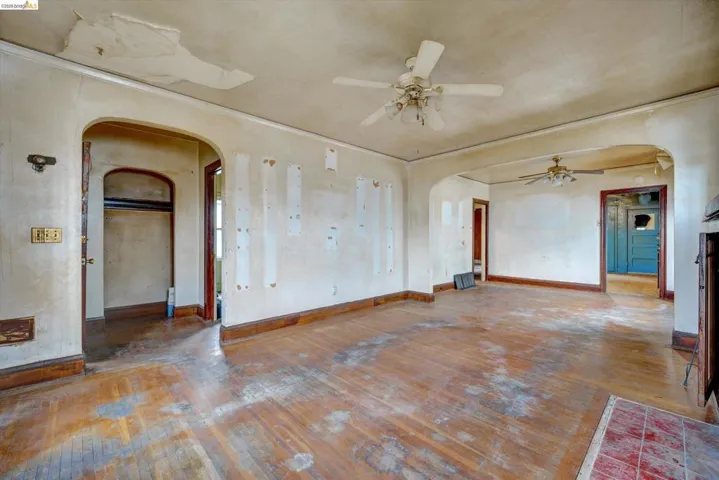 Empty room with arched walkways, hardwood / wood-style flooring, and a ceiling fan