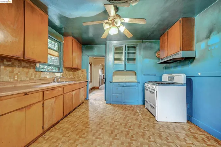 Kitchen featuring double oven range, light countertops, a ceiling fan, parquet flooring, and backsplash