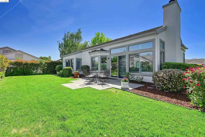Rear view of house featuring stucco siding, a chimney, and a patio area
