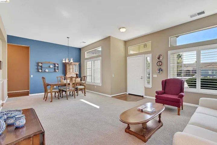 Living room with light colored carpet, plenty of natural light, and a chandelier