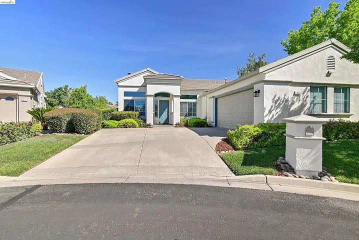 View of front of property with stucco siding, a garage, concrete driveway, and a front yard