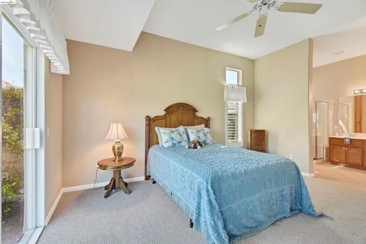 Bedroom with light carpet, ceiling fan, and connected bathroom
