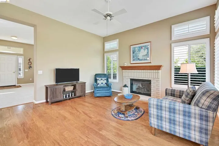 Living area with light wood-style floors, a ceiling fan, and a fireplace