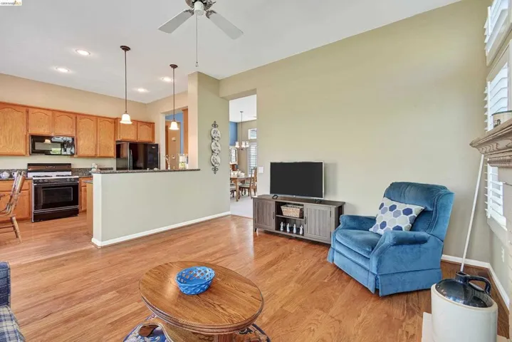 Living room featuring light wood-style flooring, a brick fireplace, ceiling fan, and recessed lighting