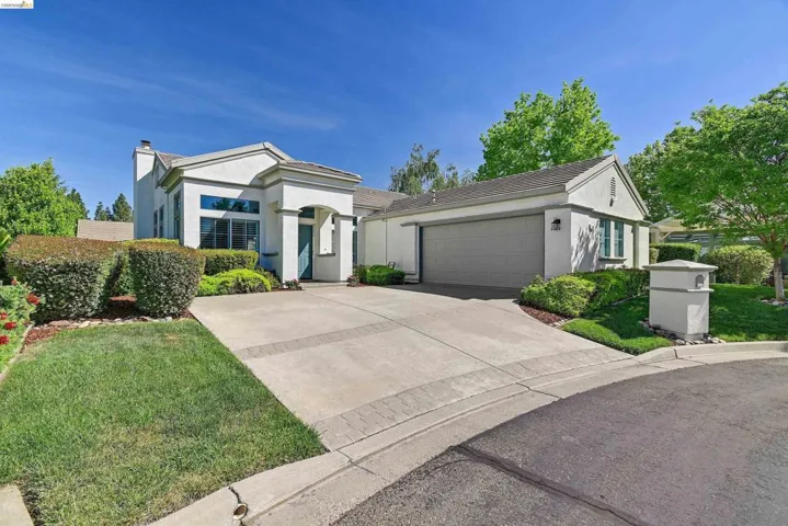 View of front of home with stucco siding, a garage, a front yard, and driveway
