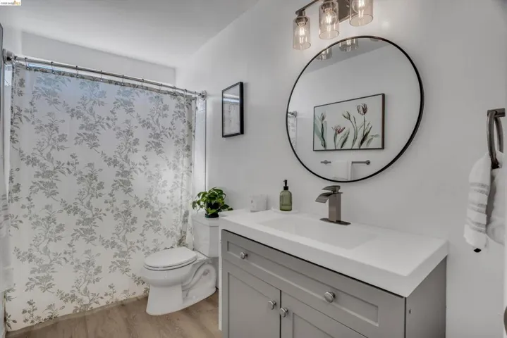 Bathroom featuring vanity, curtained shower, and light wood-style floors