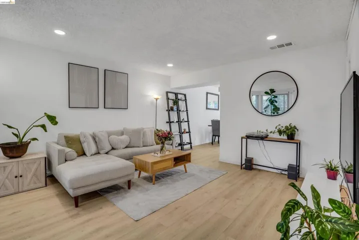 Living area with light wood finished floors, a textured ceiling, and recessed lighting