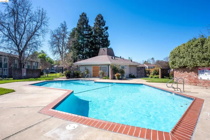 Community pool with a patio area and a residential view