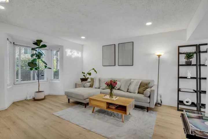 Living area with light wood-type flooring, a textured ceiling, and recessed lighting