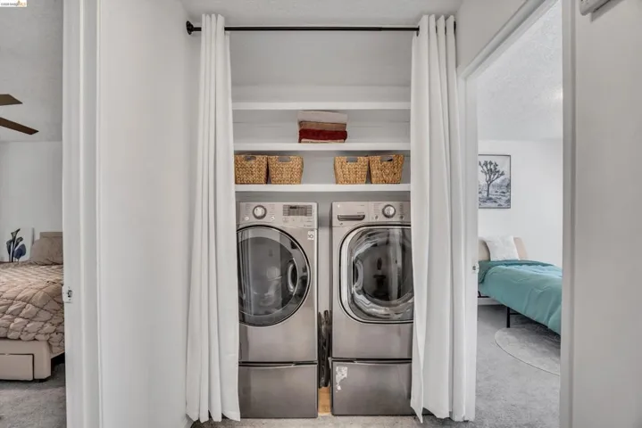 Laundry room featuring separate washer and dryer, a textured ceiling, light colored carpet, and ceiling fan