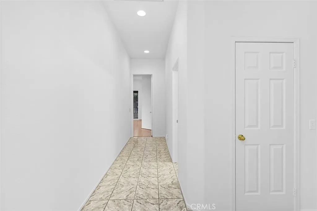 The hallway shows the second hall closet w/built-in shelving, the entry to hall bathroom and primary bedroom suite in the distance.