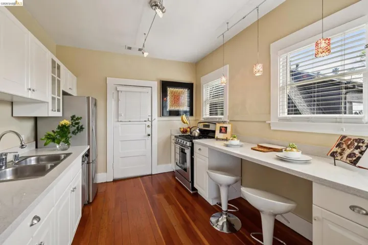 Kitchen featuring white cabinets, stainless steel appliances, glass insert cabinets, dark wood finished floors, and light stone counters