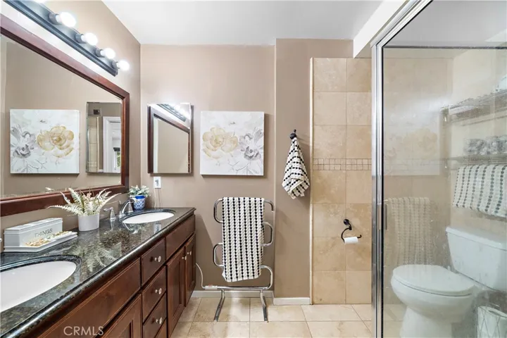 ensuite bathroom with floor-to-ceiling travertine-style tile