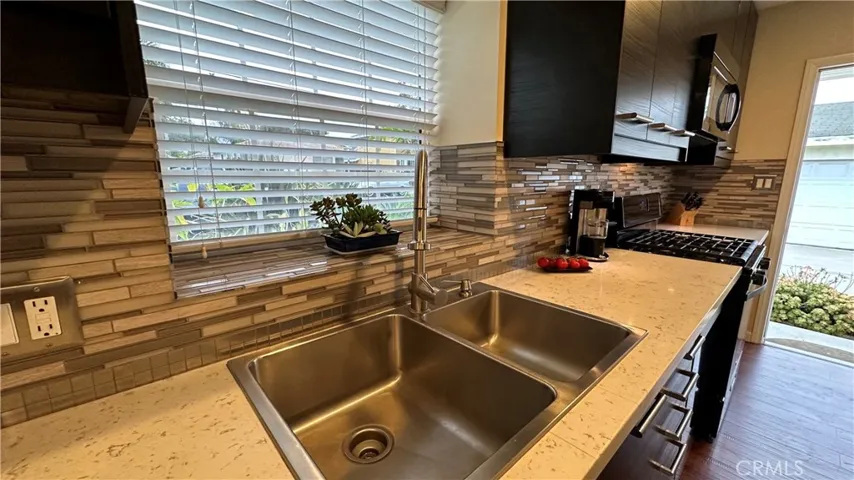 Fully remodeled kitchen with double sink, quartz counter, natural light and back access to the side.