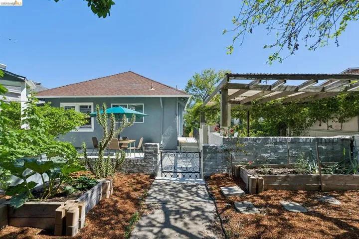 Back of house with a vegetable garden, a shingled roof, a patio area, and a gate