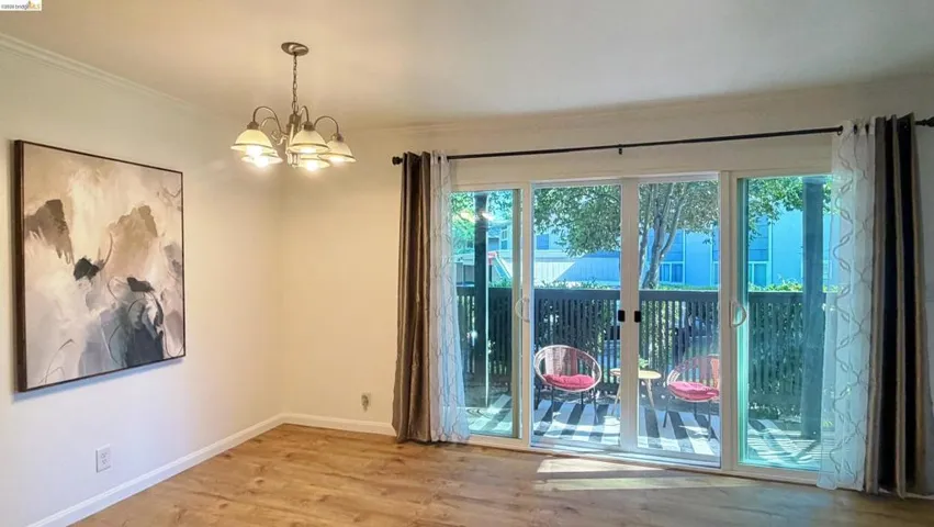 Unfurnished room with light wood-style flooring, hanging lights, and ornamental molding