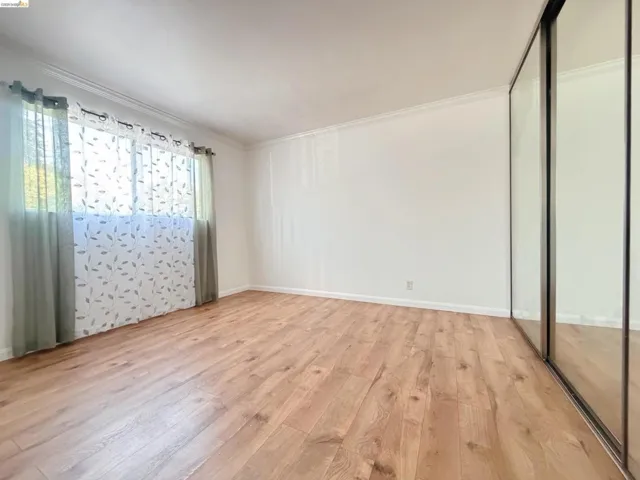 Unfurnished bedroom with light wood-style flooring, ornamental molding, and a closet