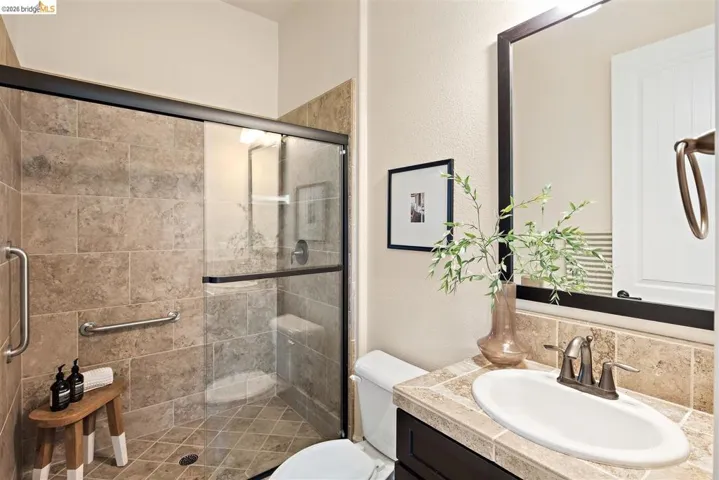 Bathroom with a textured wall, vanity, and a stall shower