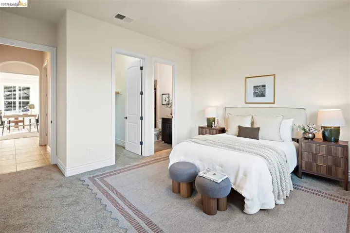 Bedroom featuring light carpet, a walk in closet, and ensuite bathroom