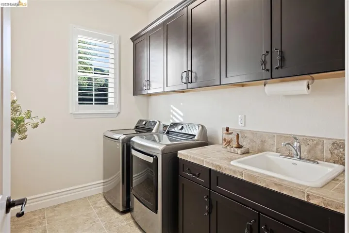 Laundry area with cabinet space, washing machine and clothes dryer, and light tile patterned floors
