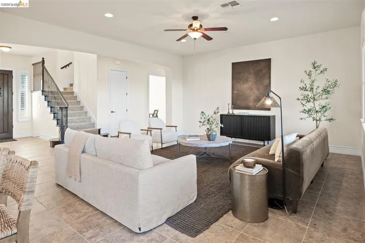 Living room featuring recessed lighting, ceiling fan, light tile patterned flooring, and arched walkways