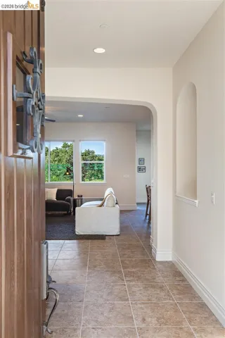 Hallway with recessed lighting, arched walkways, and light tile patterned floors