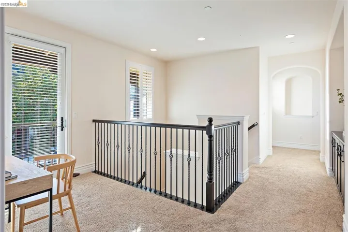 Hallway with light colored carpet, recessed lighting, and an upstairs landing