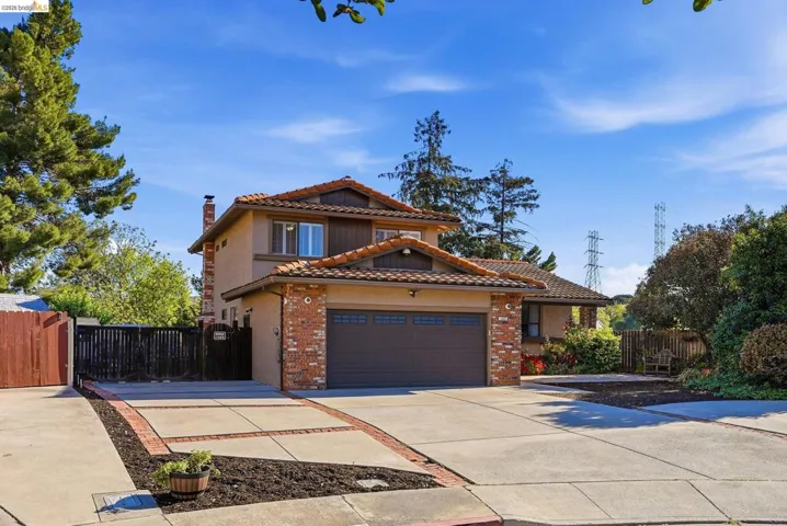 Mediterranean / spanish-style house featuring driveway, an attached garage, brick siding, a chimney, and a tile roof