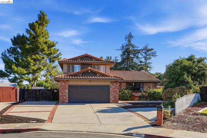 Mediterranean / spanish-style home featuring a tiled roof, driveway, an attached garage, and brick siding