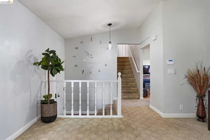 Hallway featuring light colored carpet and lofted ceiling